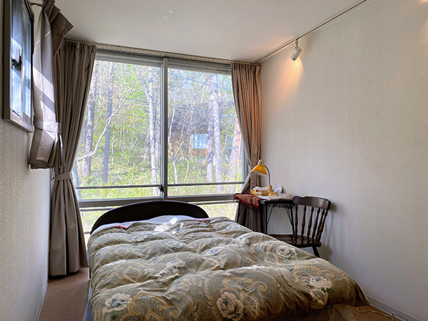 2階の寝室１。窓には周囲の緑が映る。