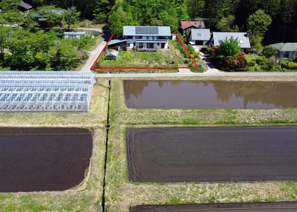 森を背にし、前面に田園風景が広がる立地。