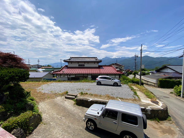 敷地は一段下がって砂利敷きの駐車場が広がる。